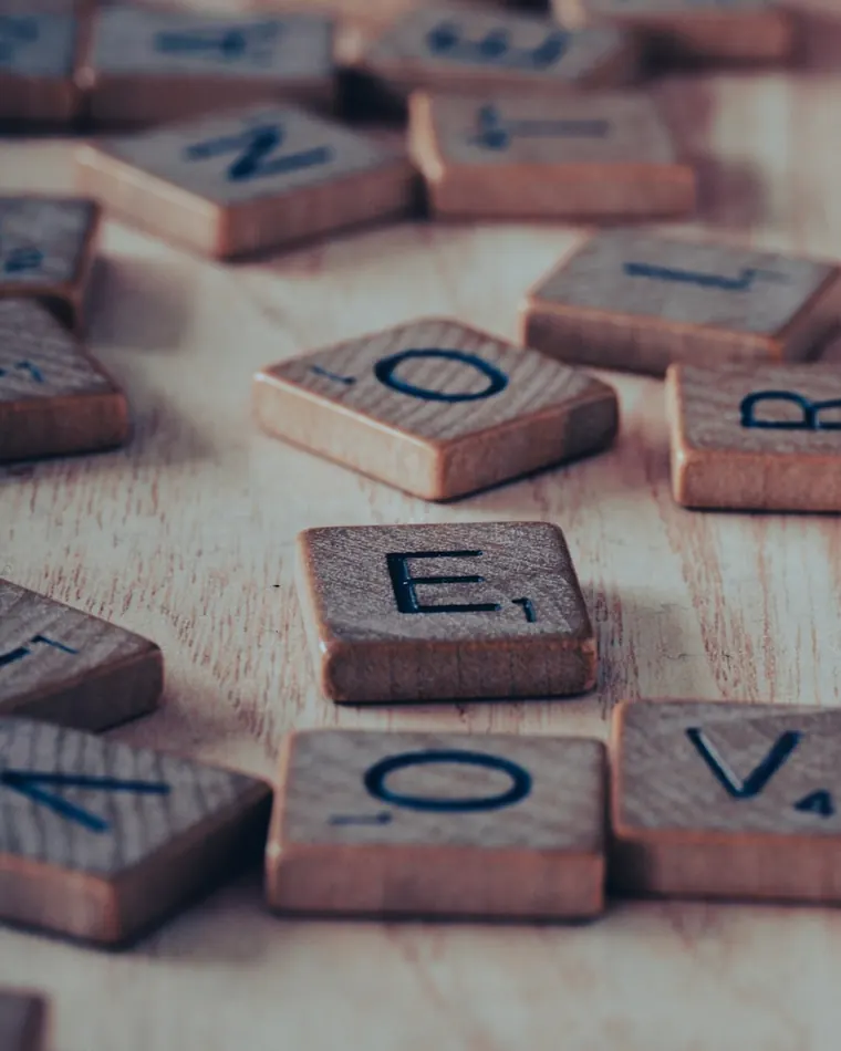 Close-up of wooden Scrabble letter tiles — the kind of rack an anagram solver unscrambles into words